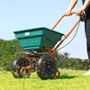 A person is using a fertilizer spreader on a grassy lawn. Produktbild-Vorschau