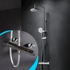 A modern chrome shower system with a rain shower head and a handheld shower head, mounted on a dark gray wall. A close-up inset shows the thermostat control. Produktbild-Vorschau