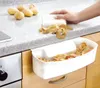 A person is peeling potatoes over a white kitchen bin attached to a drawer. Náhled obrázku produktu