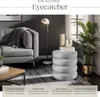 A living room scene with a sofa, floor lamp, and a decorative stool. Produktbild-Vorschau
