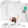 A woman is stretching in bed, surrounded by pillows and duvets, with product packaging visible. Produktbild-Vorschau