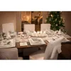 A beautifully set dining table for a festive occasion, possibly Christmas, with a decorated Christmas tree in the background. Náhled obrázku produktu
