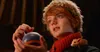 A young boy with red hair and a furry hat holds a blue and orange ornament, with a small mouse on his shoulder. Náhľad obrázku produktu