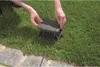 A person's hands are shown closing a gray junction box on a lawn. Produktbild-Vorschau
