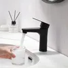 A black faucet in a bathroom, filling a glass with water. Náhľad obrázku produktu
