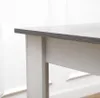 A close-up view of the edge of a table, showing the top surface and a table leg. Voir les images du produit