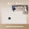 A person is sitting on a couch while a robot vacuum cleans the floor in a serpentine pattern. Produktbild-Vorschau