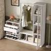 A white entryway organizer with a hanging rack, bench, and storage compartments, set against a green wall and a curtain. Produktbild-Vorschau