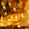 A close-up of a string of Christmas lights shaped like bells, placed in a woven basket. Náhled obrázku produktu