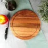 A wooden cutting and serving board is shown on a light gray surface, with an apple, a knife, a bottle of olive oil, and a sprig of rosemary arranged around it. Voir les images du produit