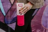 A person is holding a pink and white Kambukka thermoflasche in front of a colorful mural. Náhled obrázku produktu