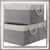 Two gray storage baskets are stacked on top of each other, with a third basket partially visible to the right. Anteprima dell’immagine prodotto
