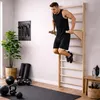 A man is performing a dip exercise on a wooden wall-mounted gym ladder in a home gym setting. Produktbild-Vorschau