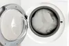 A close-up view of a washing machine with the door open, revealing laundry inside. Produktbild-Vorschau