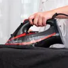 A person is ironing black fabric with a black and red steam iron. Náhľad obrázku produktu