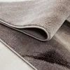A close-up view of a rolled-up rug, showing its texture and abstract pattern. Produktbild-Vorschau