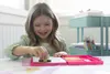 A young girl is happily using a creative set at a table. Anteprima dell’immagine prodotto