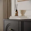 A close-up of a black dresser with decorative elements and items on top, including books, a diffuser, and a decorative bowl. Produktbild-Vorschau