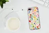 A flat lay of a phone case with a floral pattern, a cup of coffee, and earphones on a white surface. Produktbild-Vorschau