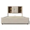 A beige upholstered bed frame with a headboard featuring built-in storage shelves, shown against a white background. Anteprima dell’immagine prodotto