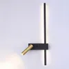 A modern black and gold wall lamp mounted on a white wall. Produktbild-Vorschau