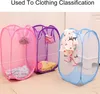 Three pop-up laundry baskets in pink, purple, and blue, filled with clothes, are displayed on a tiled floor. Produktbild-Vorschau