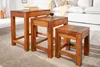 Three wooden nesting tables of varying sizes arranged on a rug in a living room setting. Produktbild-Vorschau