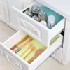 Two open drawers of a white cabinet, showing kitchen utensils and jars. Produktbild-Vorschau