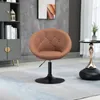 A brown upholstered swivel chair with a black base is placed on a light blue and white patterned rug in a room with a gray cabinet and a marble-patterned wall. Produktbild-Vorschau