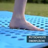 A person's foot is stepping onto a blue mat with a textured surface, with grass visible in the background. Produktbild-Vorschau