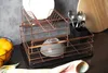 A copper dish rack with dishes, a bowl, and cutlery on a countertop. Anteprima dell’immagine prodotto