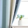 A close-up view of gradient curtains with star patterns, next to a window, with a vase of artificial flowers on a white surface. Náhled obrázku produktu
