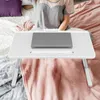 A person is using a laptop on a bed with a portable table. Produktbild-Vorschau