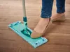 A person is mopping a wooden floor with a turquoise mop. Produktbild-Vorschau