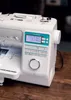 A close-up shot of a white Brother Innov-is A65 sewing machine, placed on a wooden surface. Produktbild-Vorschau