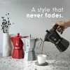 A hand is pouring coffee from a black Moka pot into a white cup, with a red and a silver Moka pot in the background. Anteprima dell’immagine prodotto