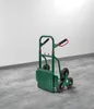 A green stair-climbing hand truck is shown in a room with a white wall and a concrete floor. Produktbild-Vorschau