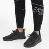 A person wearing black Puma sports shoes and black Puma pants. Produktbild-Vorschau