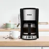 A coffee maker is shown on a kitchen counter next to a cup of coffee. Produktbild-Vorschau