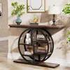 A console table with a circular shelf unit is placed against a textured wall, decorated with a vase of greenery, a gold swan sculpture, books, a vintage radio, and decorative boxes. Anteprima dell’immagine prodotto