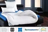 A white duvet and pillows are arranged on a bed with a blue sheet. Produktbild-Vorschau