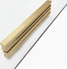 A gold-colored shower door profile is placed diagonally on a white background next to a thin black rod. Náhľad obrázku produktu
