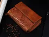 A brown leather wallet with a woven detail is placed on a black surface with coffee beans scattered around it. Náhľad obrázku produktu