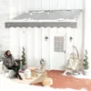A woman sits on a chair on a snow-covered patio next to a white house with a gray awning. Náhľad obrázku produktu