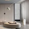 A modern living room with a large arc floor lamp, an ottoman, and a side table. Anteprima dell’immagine prodotto