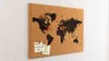 A cork world map pinboard mounted on a white wall, with red pins marking locations and two small yellow sticky notes attached. Produktbild-Vorschau