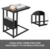 A black side table with a book and mug on top, and a magazine rack on the side. Náhľad obrázku produktu