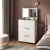 A white dresser with a mirror and makeup is placed next to a bed in a bedroom. Náhľad obrázku produktu