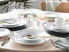 A table setting with white plates, bowls, glasses, and gold cutlery. Produktbild-Vorschau