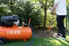 A person is using an air compressor and a jackhammer in a garden. Produktbild-Vorschau